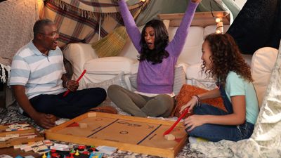 Image of a father, a mother and a daughter playing table hockey